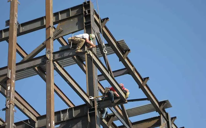 Workers bolting purlins on a steel frame, a stock photograph from the old site, not the RRTS stations